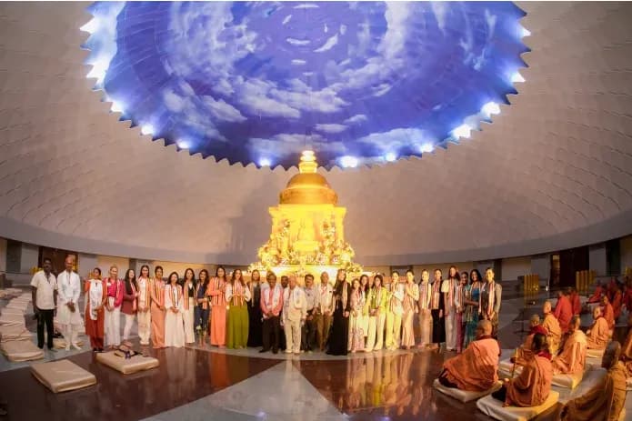 People standing before a gold shrine beneath a large blue domed ceiling