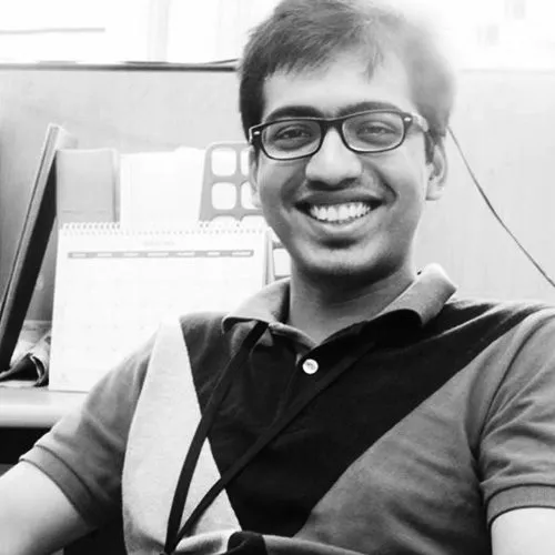 Black and white portrait of a smiling man in glasses at a desk