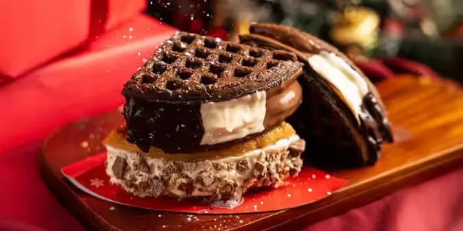 Dessert of waffles layered with ice cream and chocolate sauce on a red plate