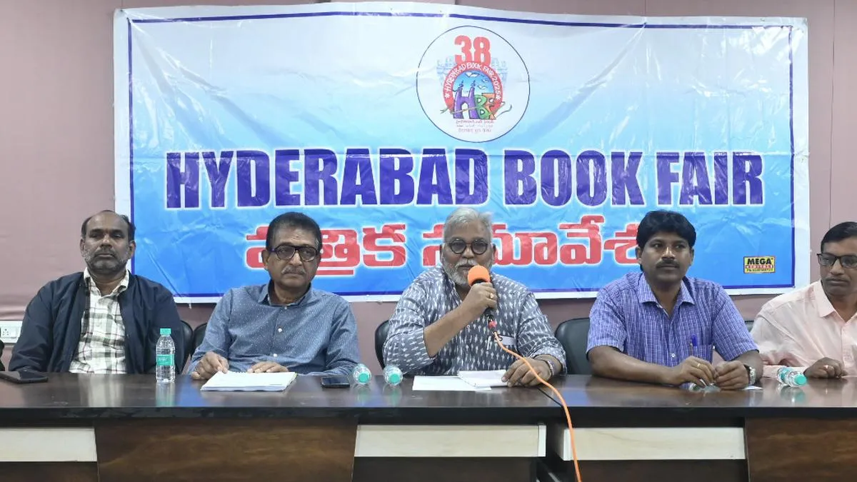 Men seated at a table with microphones beneath a book fair banner