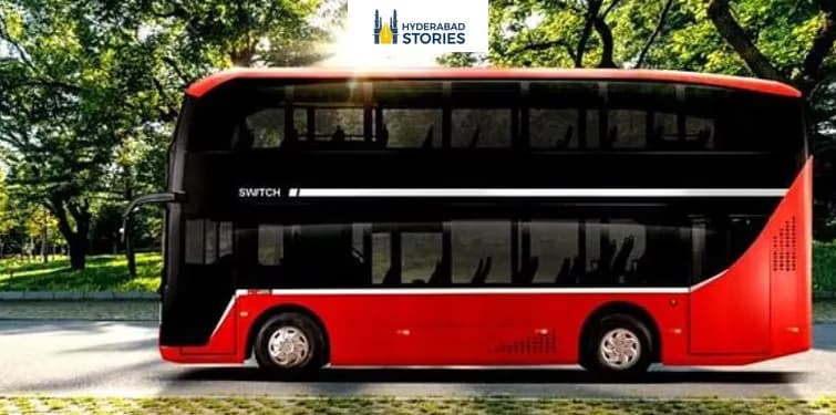 Red electric double-decker bus parked beneath trees