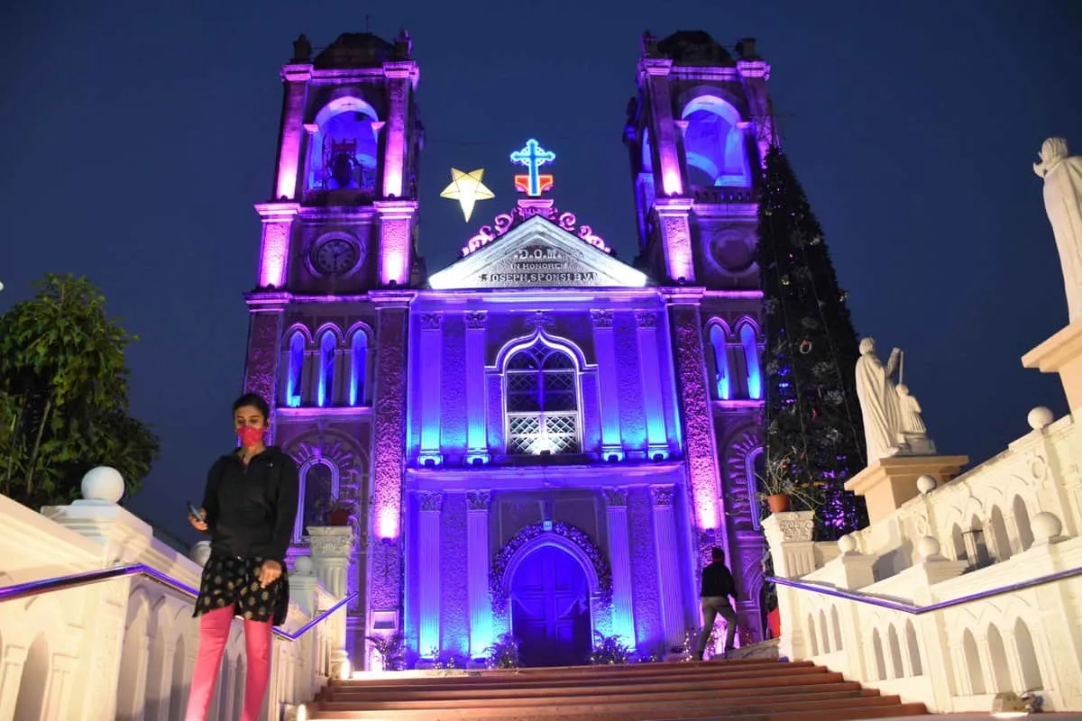 Church facade lit in purple and blue at night with a person on the steps