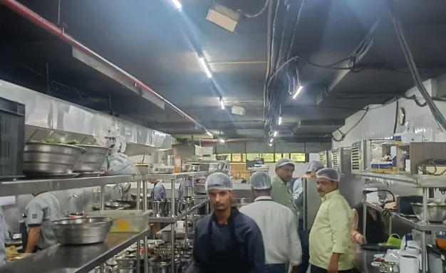 Workers in a large stainless steel commercial kitchen