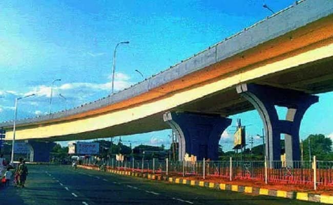 Elevated concrete flyover curving above an empty road under blue sky