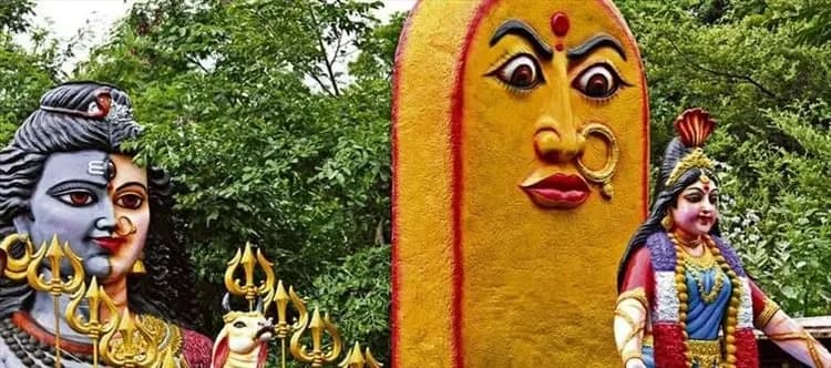 Painted deity figures on a roadside wall beside trees