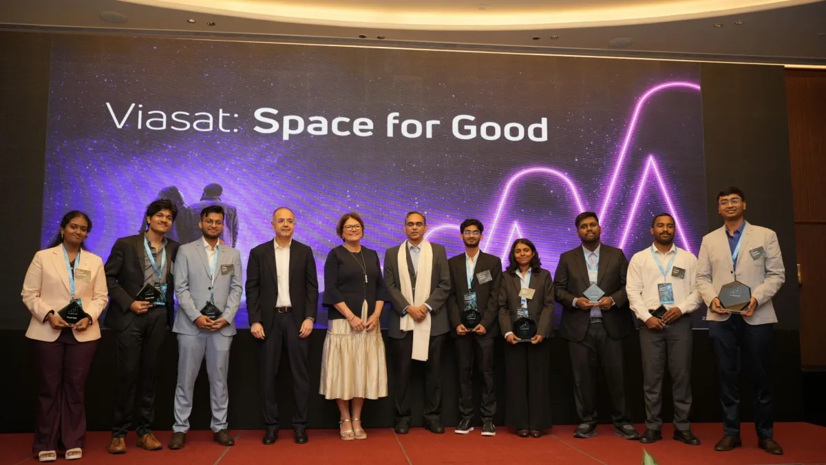 Group posed on a stage before a presentation screen