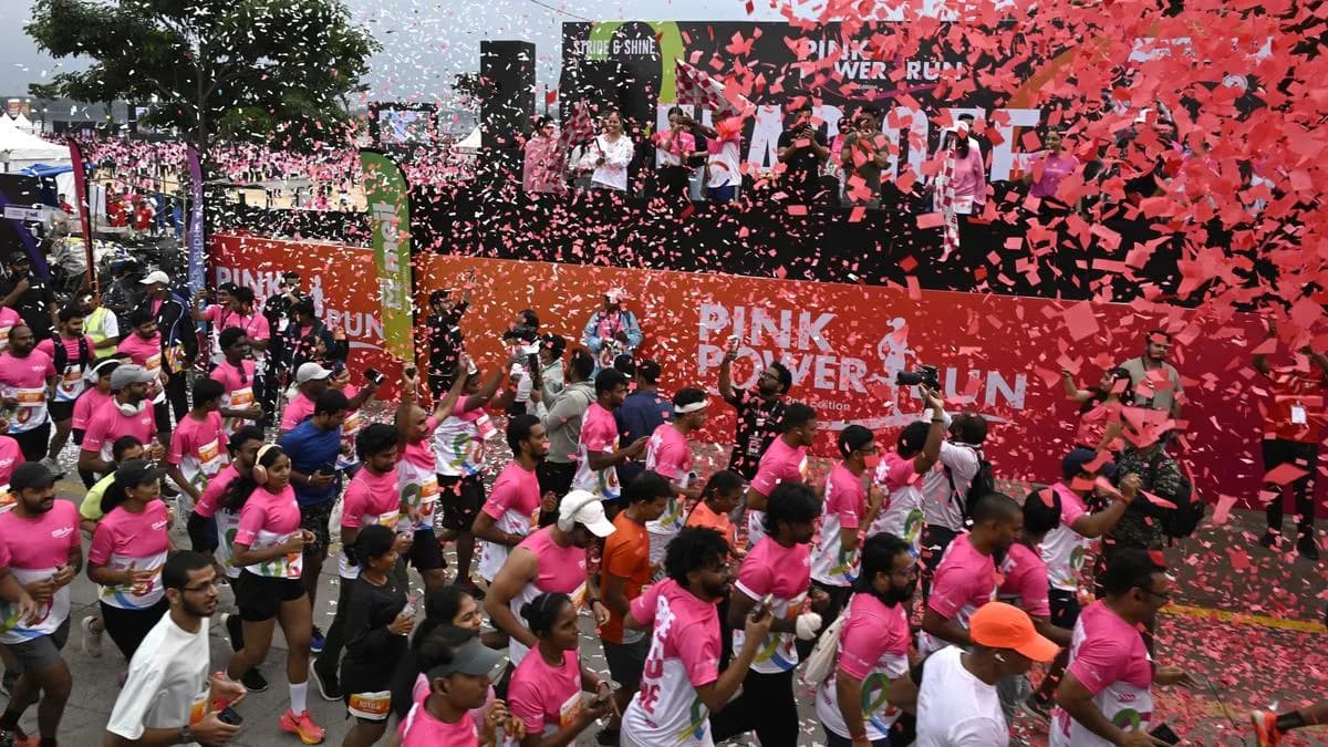 Crowd of runners in pink shirts at a start line with confetti