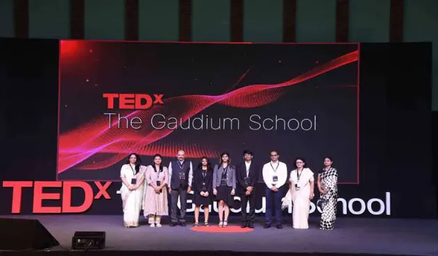 Group on a stage before a large red event screen