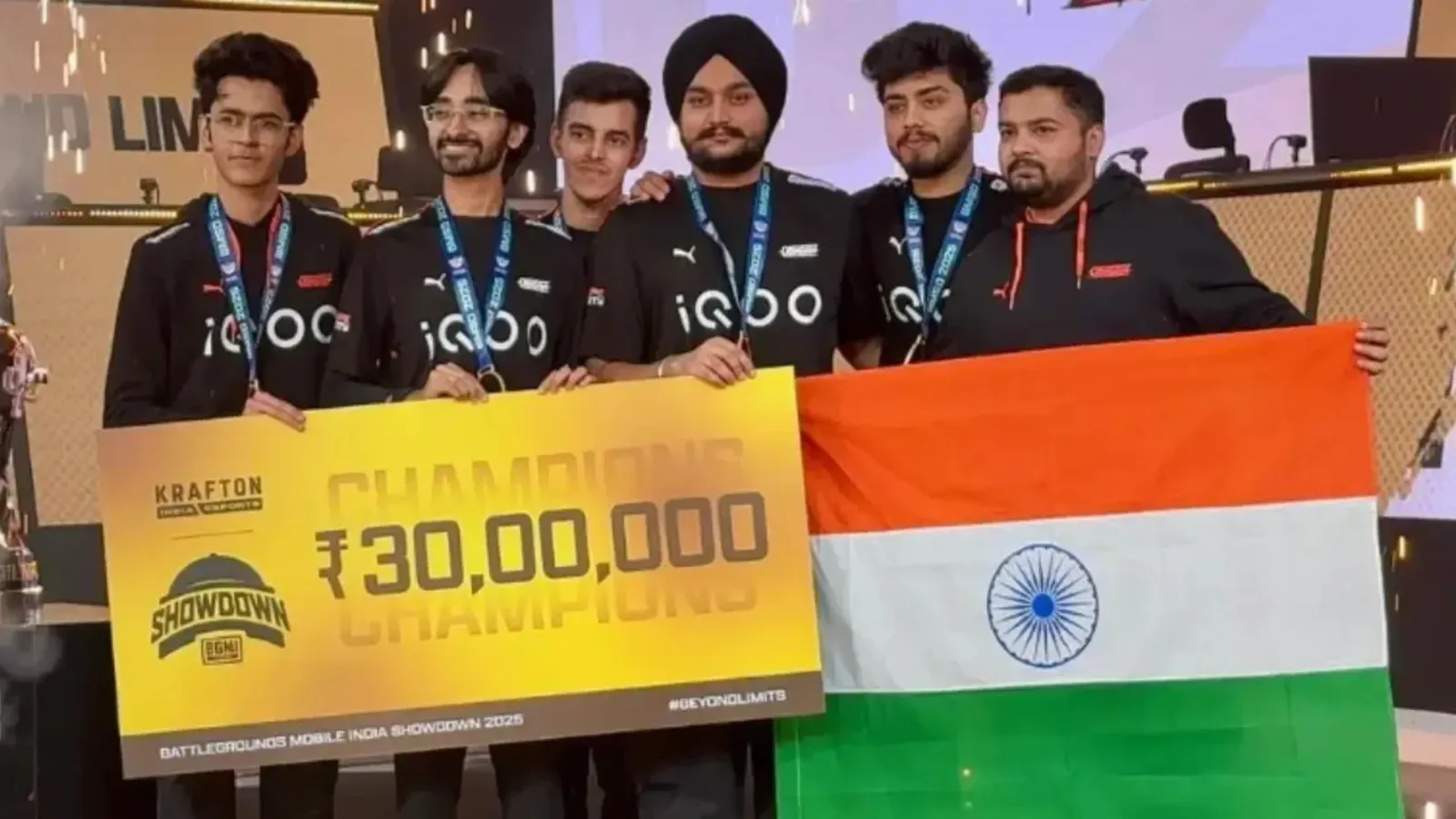 Team holding an oversized prize cheque and a flag on a stage